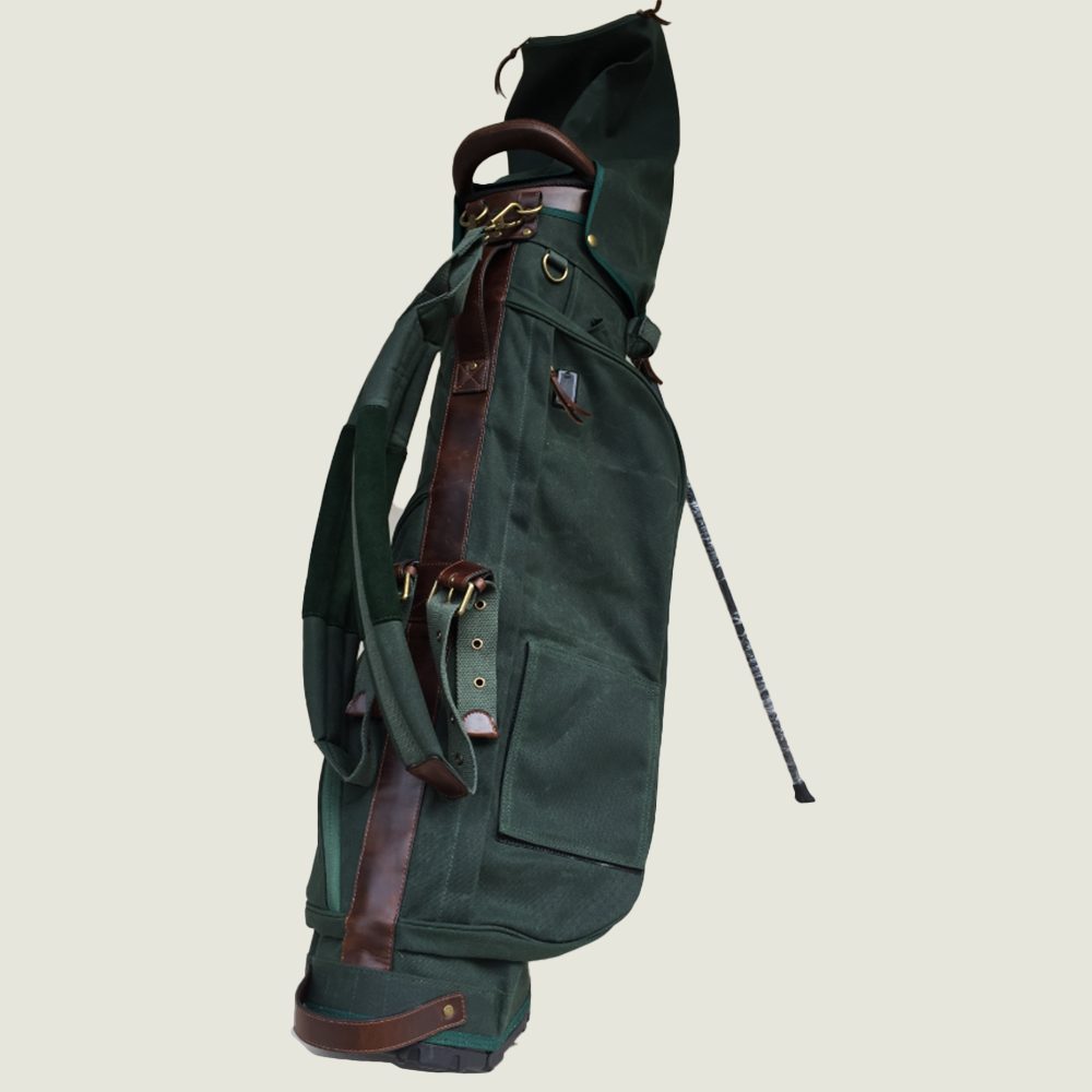 Green golf bag with brown straps on a beige background