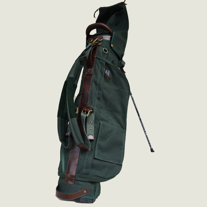 Green golf bag with brown straps on a beige background